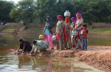women in rajasthan filling water from a pond deepened by ambuja cement foundation